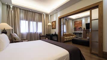 A hotel room with a large bed, a desk with a lamp, a sofa, and a television.