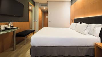 Una habitación de hotel con una cama, una mesita de noche y un escritorio con cafetera.
