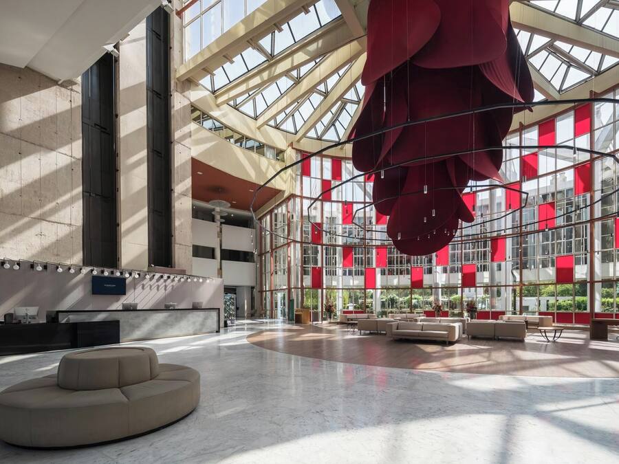A spacious atrium with a high ceiling, large windows, and a central seating area.