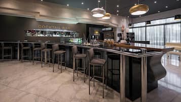 A modern cocktail bar with a marble floor, bar stools, and a well-stocked bar area.