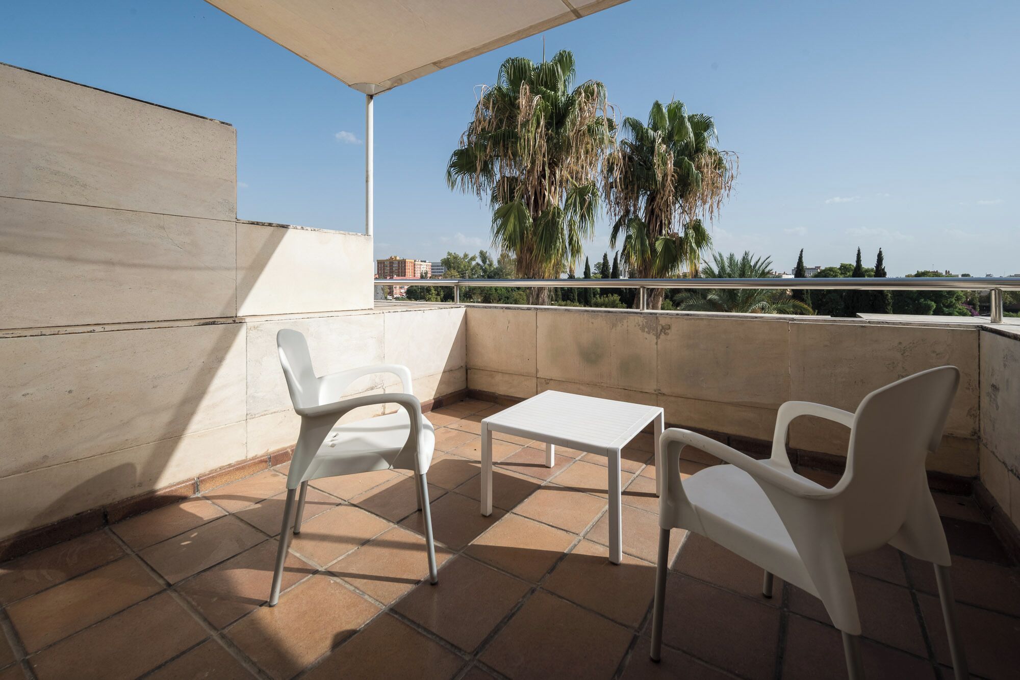 A balcony with two white plastic chairs and a small white table.