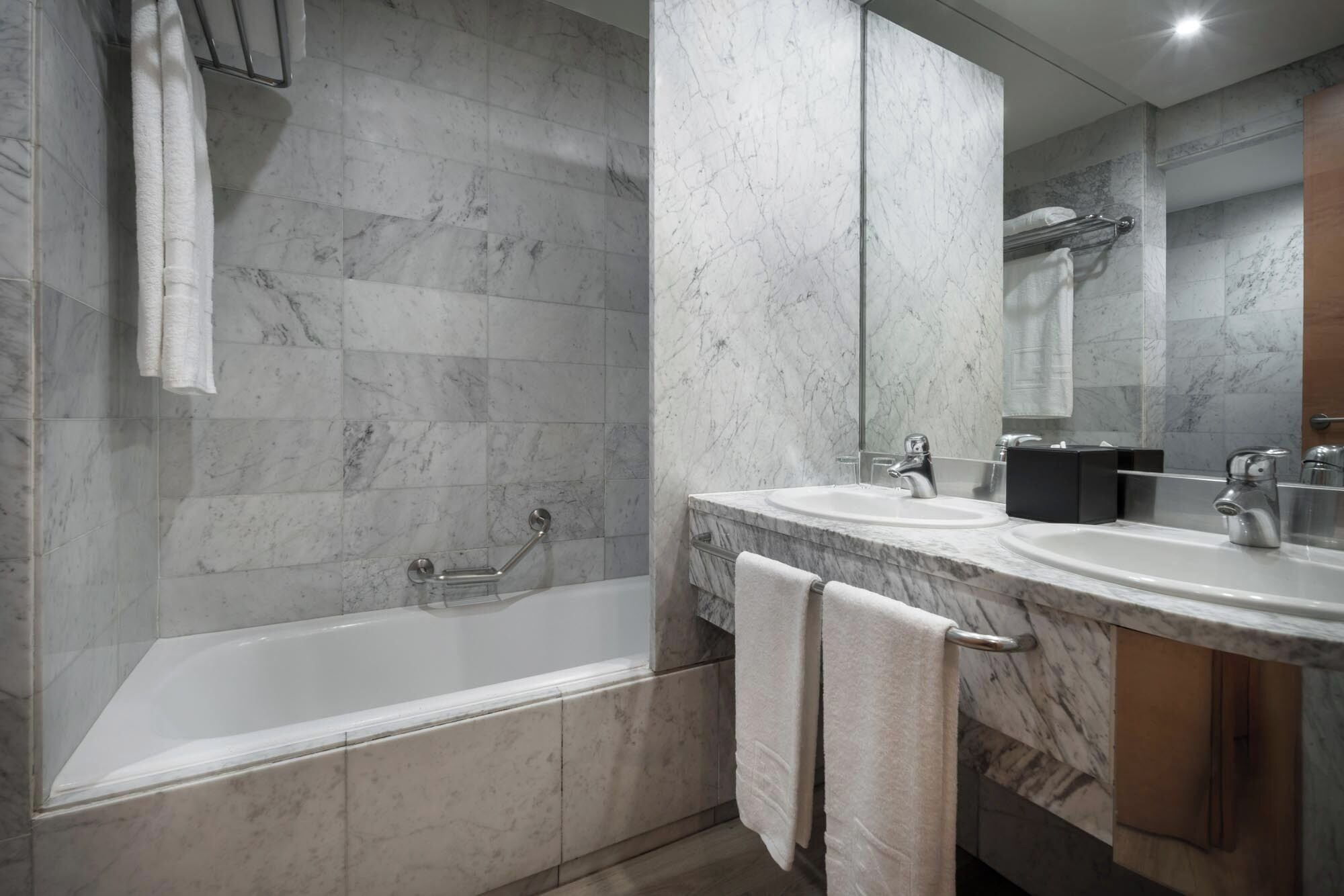 Ein modernes Badezimmer mit einer Badewanne, zwei Waschbecken und einem großen Spiegel.