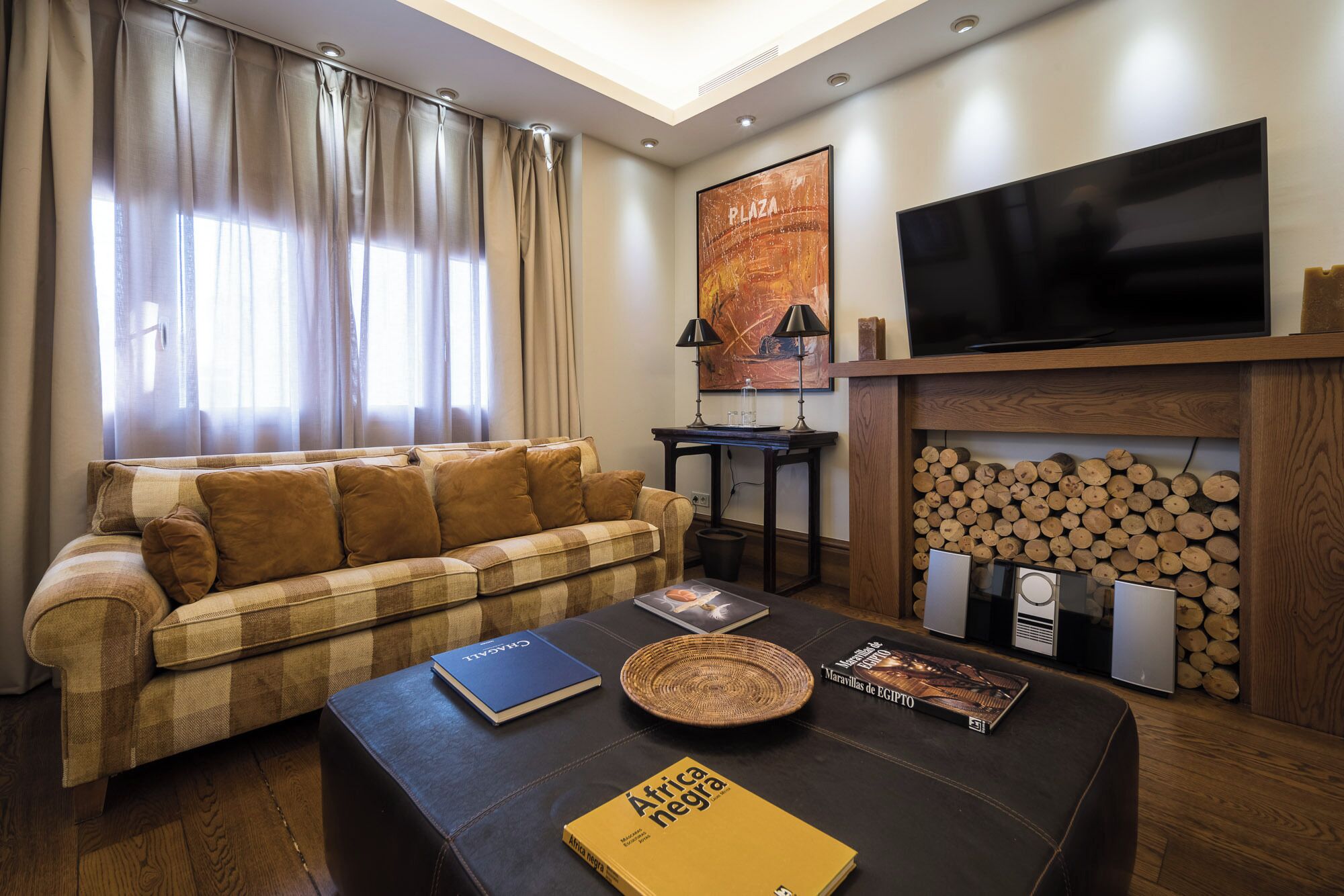 A living room with a sofa, a coffee table, a fireplace, and a television.