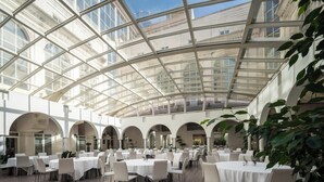 A spacious indoor dining area with multiple tables and chairs, a glass ceiling, and arches. - Eurostars Al-Ándalus Palace (Seville)