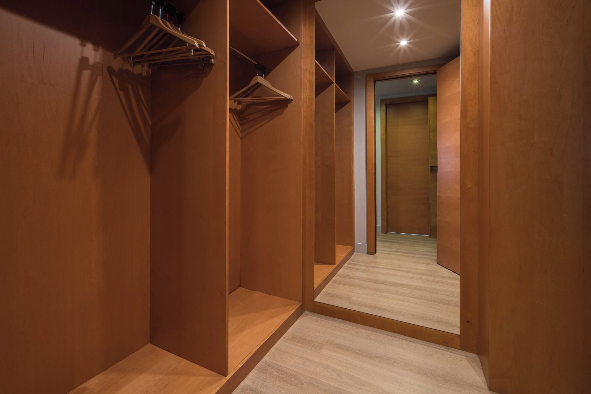 A narrow hallway with wooden walls and a wooden floor, leading to a door at the end.