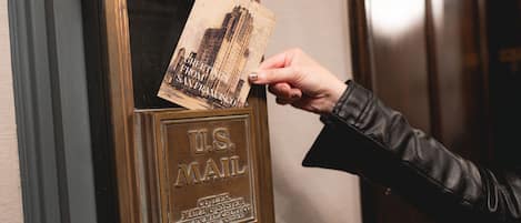 Una mano introduciendo una postal en el buzón de correo.