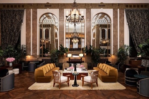 A lobby with a chandelier, seating area, and large mirrors.
