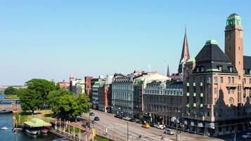 En historisk stadsbild med en framträdande byggnad som har ett klocktorn och en flod med båtar.