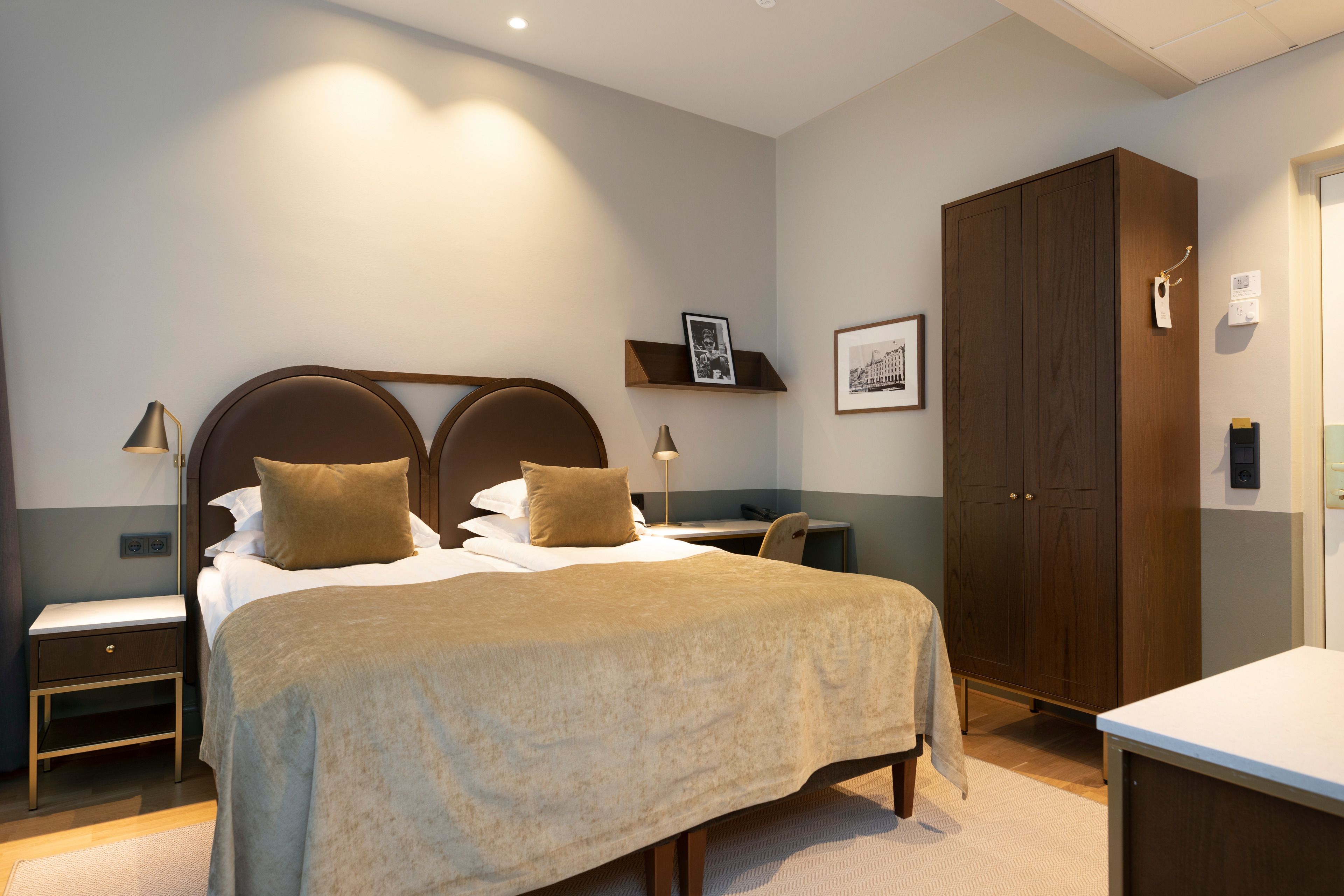 Ein Hotelzimmer mit einem großen Bett, Nachttischen, einem Kleiderschrank und einem Schreibtisch.