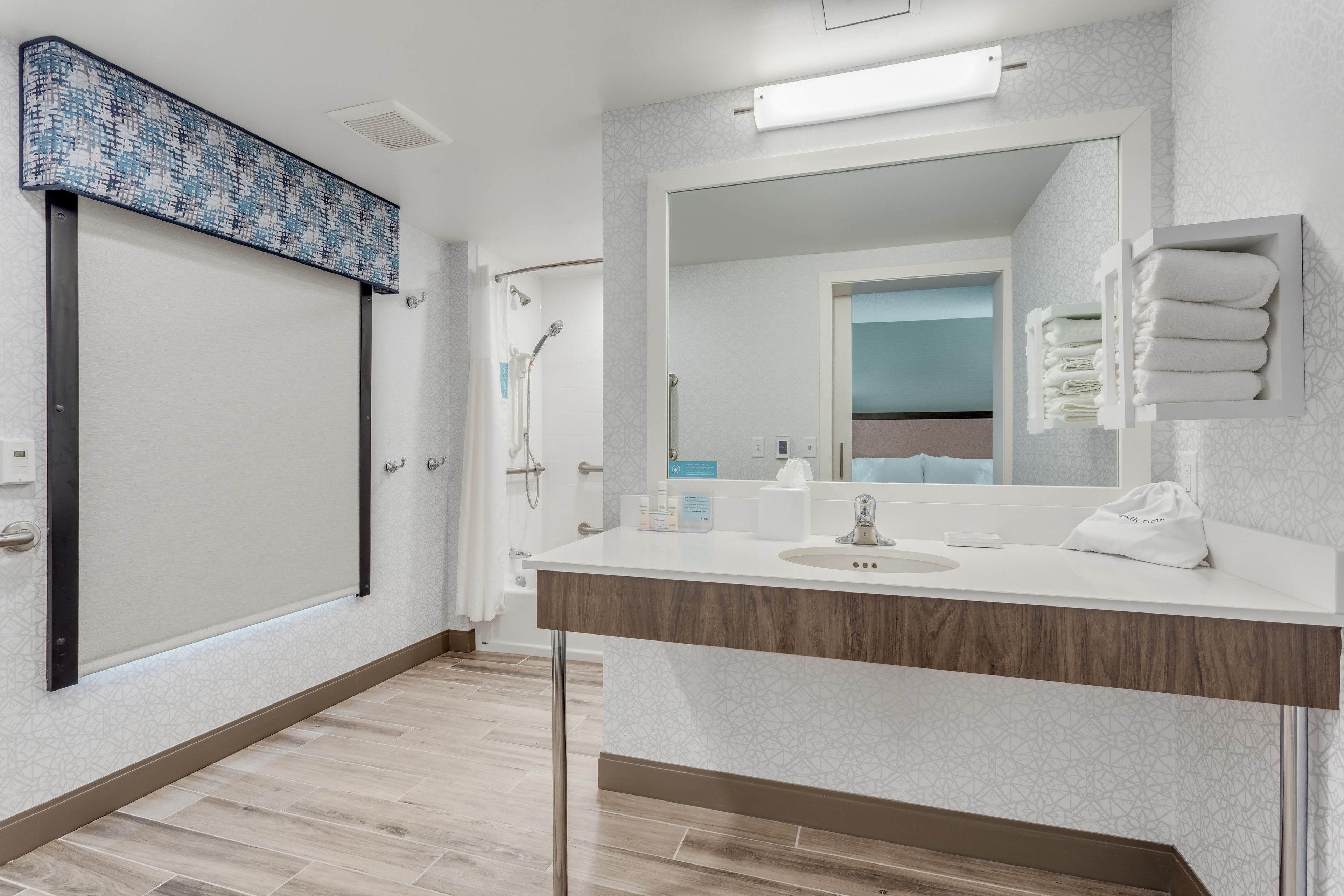 Un baño moderno con un espejo grande, un lavamanos y una ducha.