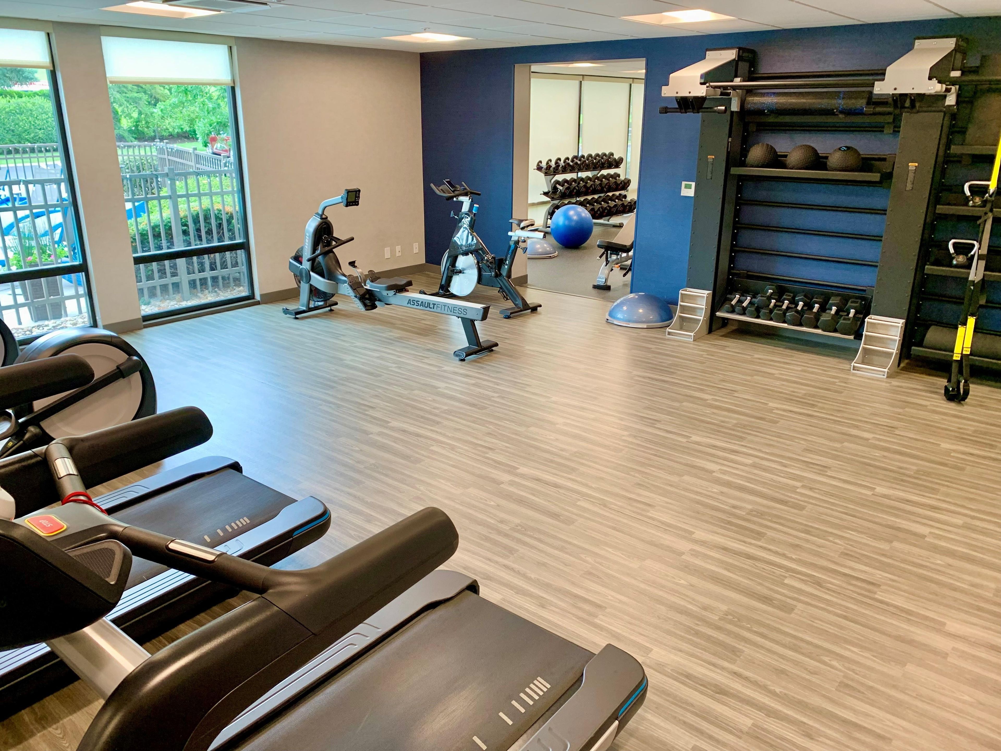 A gym with cardio machines, free weights, and exercise balls.