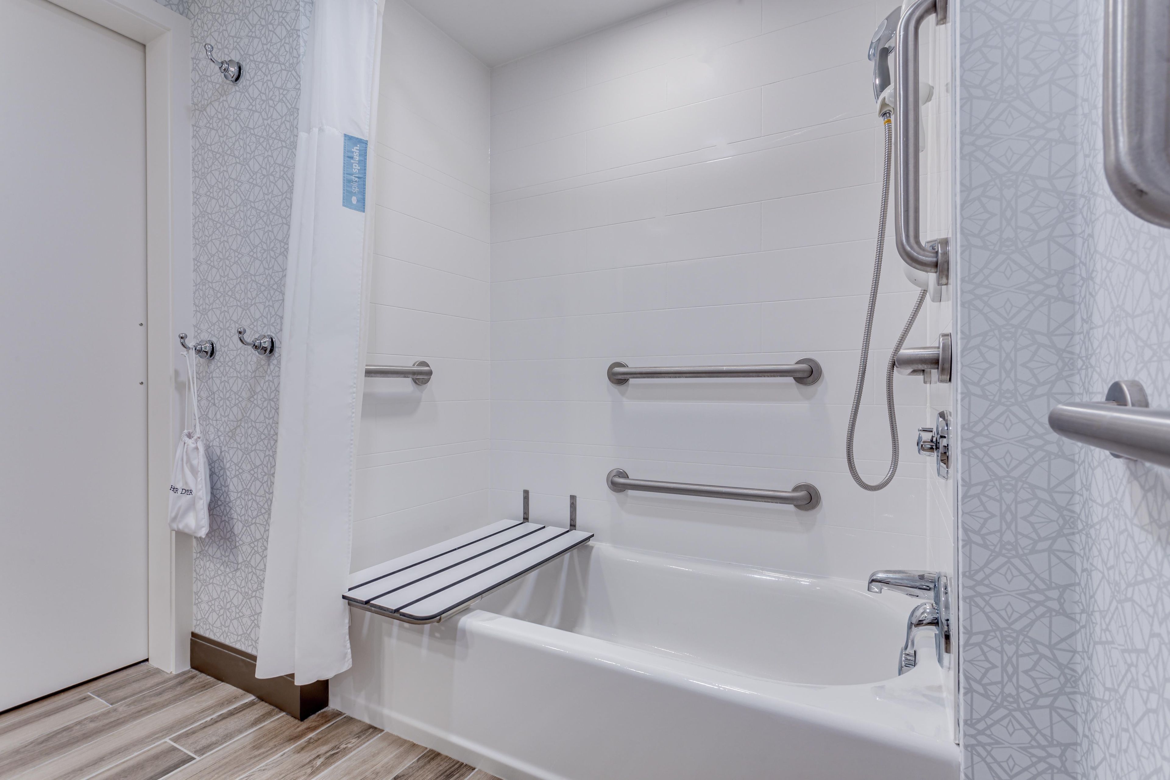 Un baño moderno con bañera, ducha y barras de apoyo.