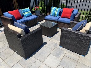 A patio area with wicker furniture, including sofas and chairs, and a central coffee table.