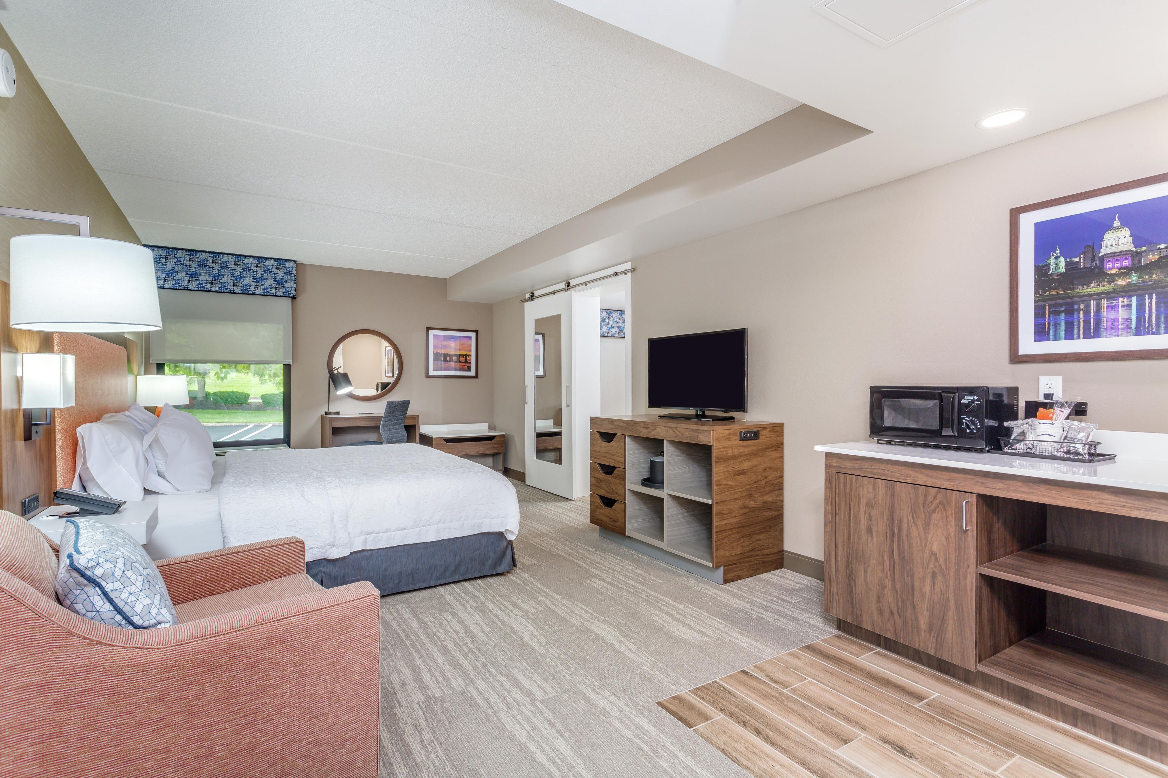 Habitación de hotel con cama, escritorio, televisión y vistas al exterior.