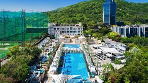 A hotel with a swimming pool, multiple buildings, and a mountainous backdrop. - BanyanTree Club & Spa Seoul (Seoul)