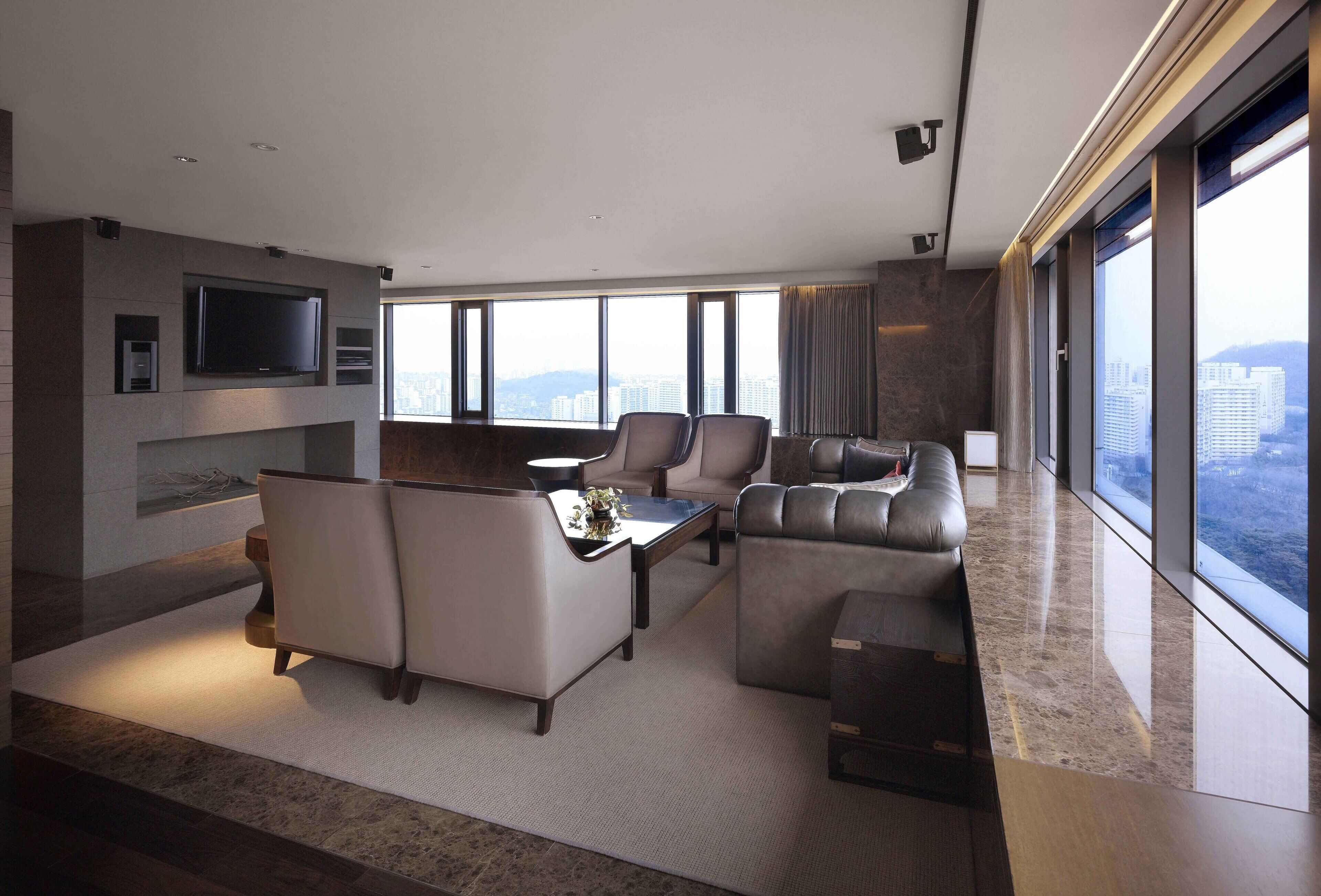 A modern living room with a flat-screen TV mounted on the wall, a sofa set, and a coffee table.