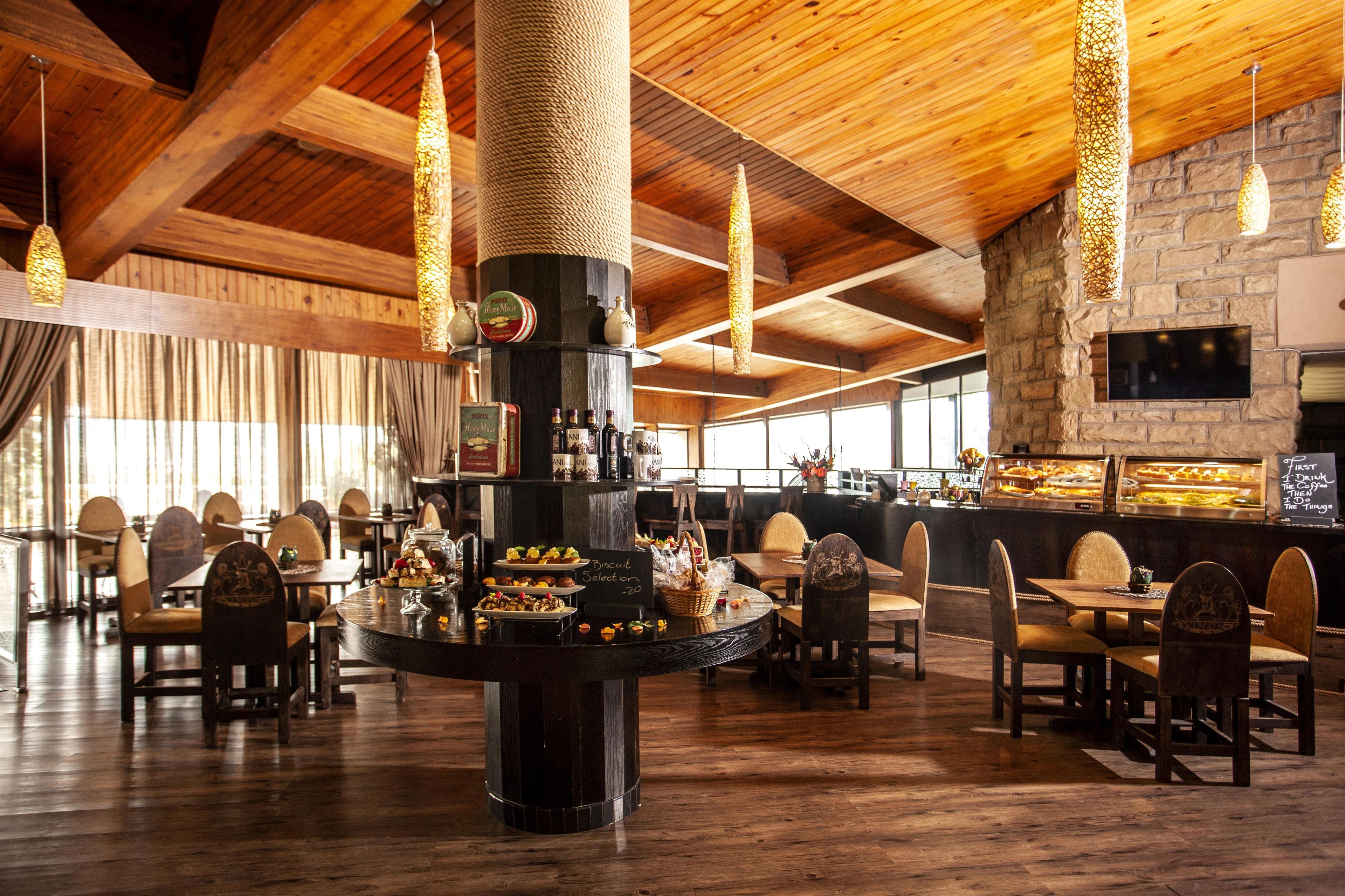 A restaurant interior with wooden beams, a central column, and a variety of seating arrangements.
