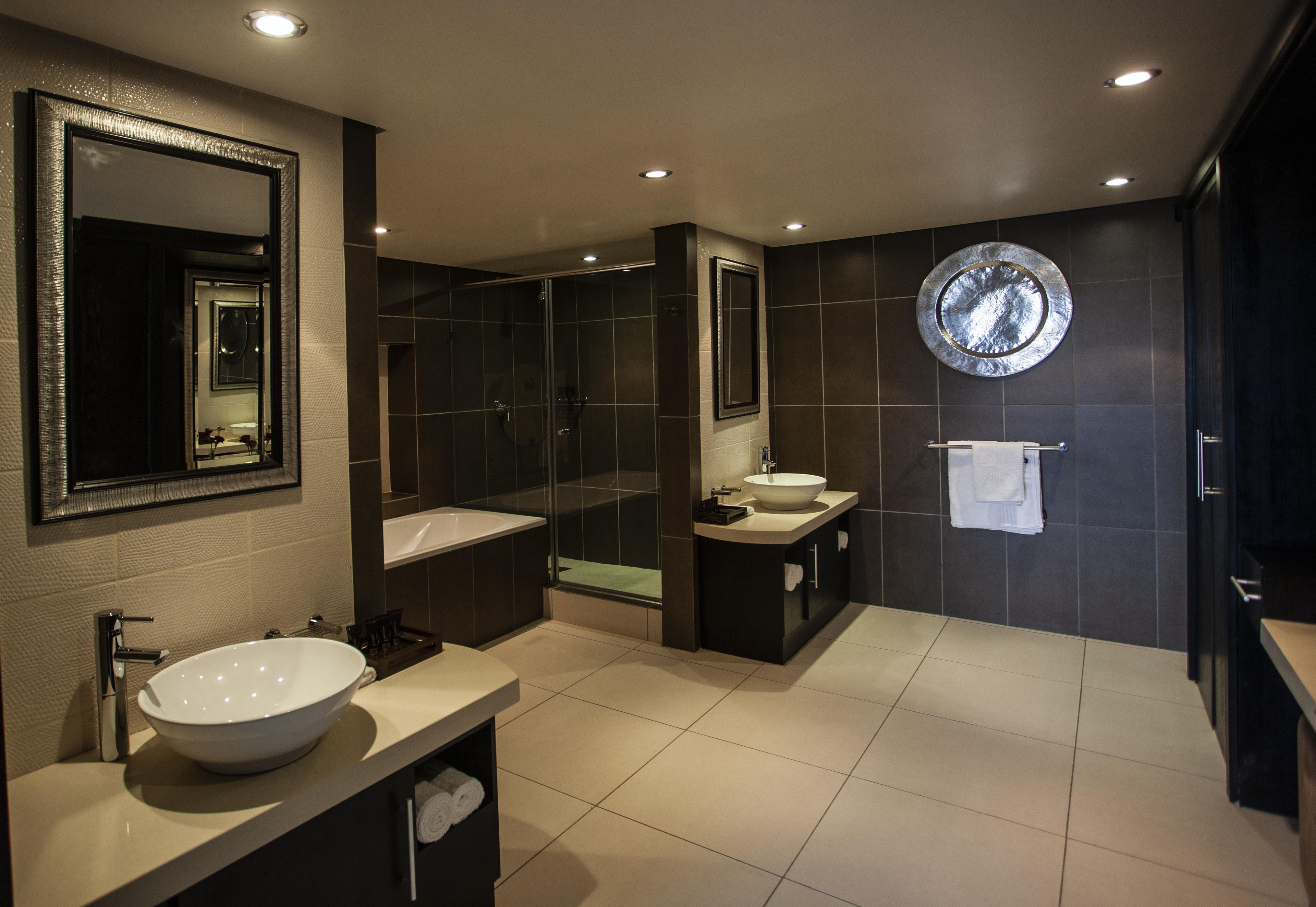 A modern bathroom with a large mirror, a bathtub, a sink, and a shower.