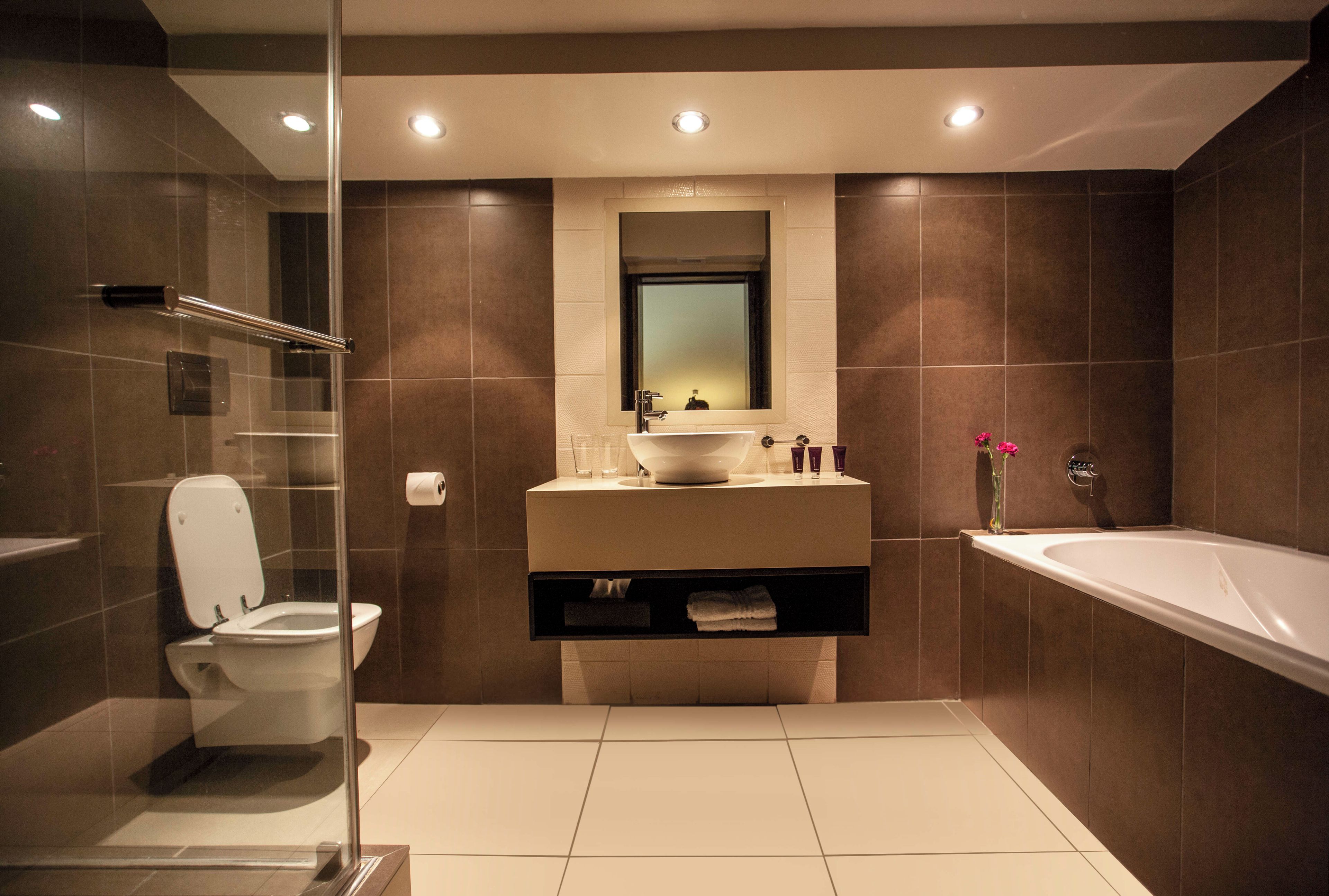 A modern bathroom with a glass shower enclosure, a white toilet, a vanity with a mirror, and a freestanding bathtub.