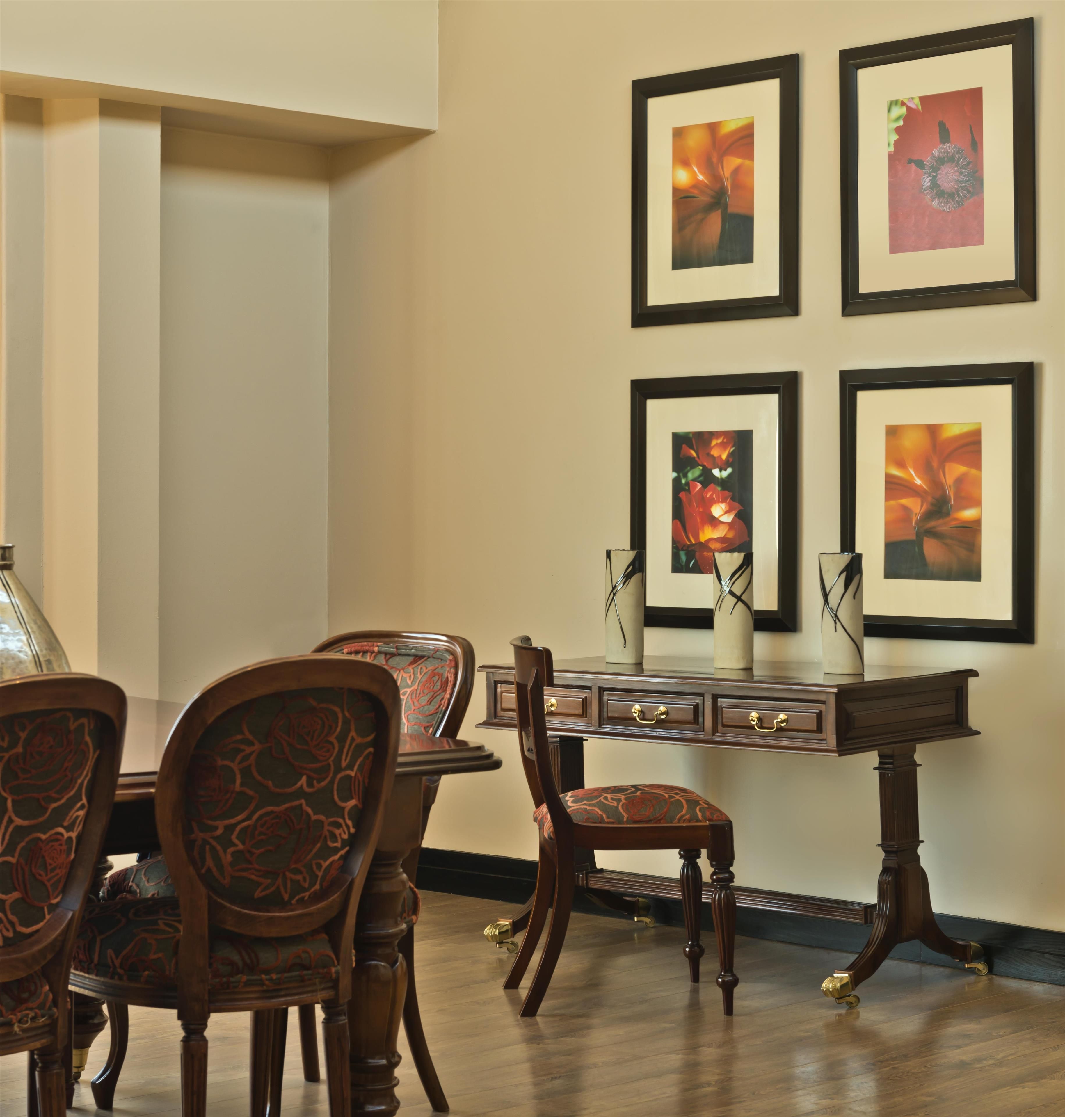 A dining area with a wooden table and chairs, a decorative vase, and framed artwork on the wall.