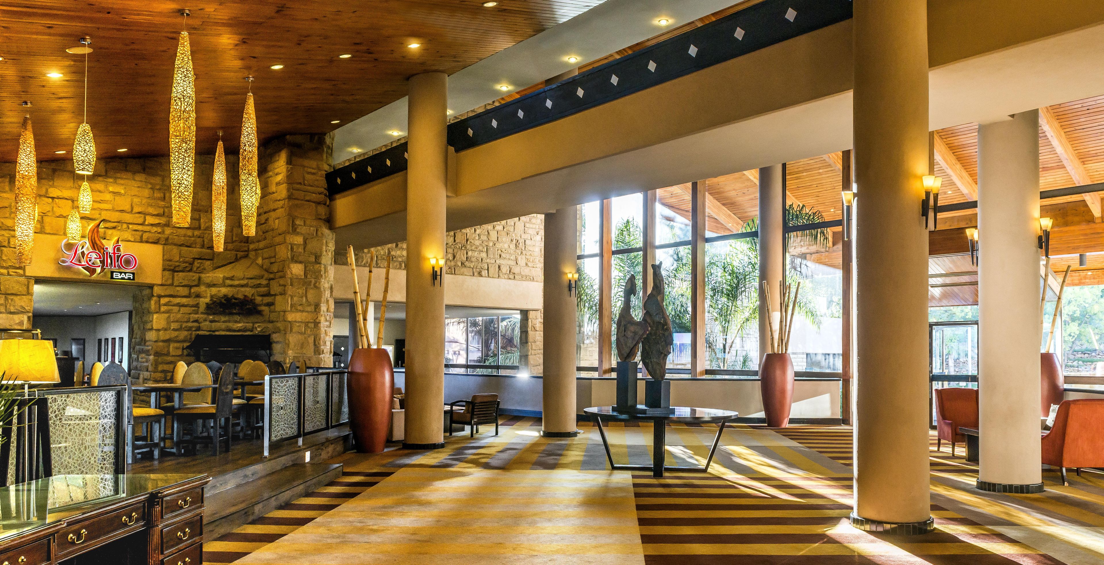 A spacious lobby with a stone wall, a bar area, and large windows allowing natural light.