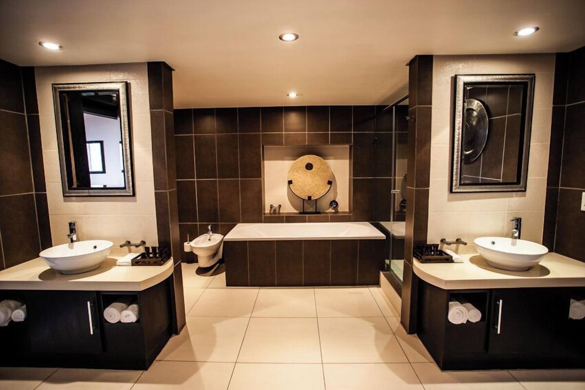 Un baño moderno con dos lavamanos, una bañera grande y un espejo sobre la bañera.