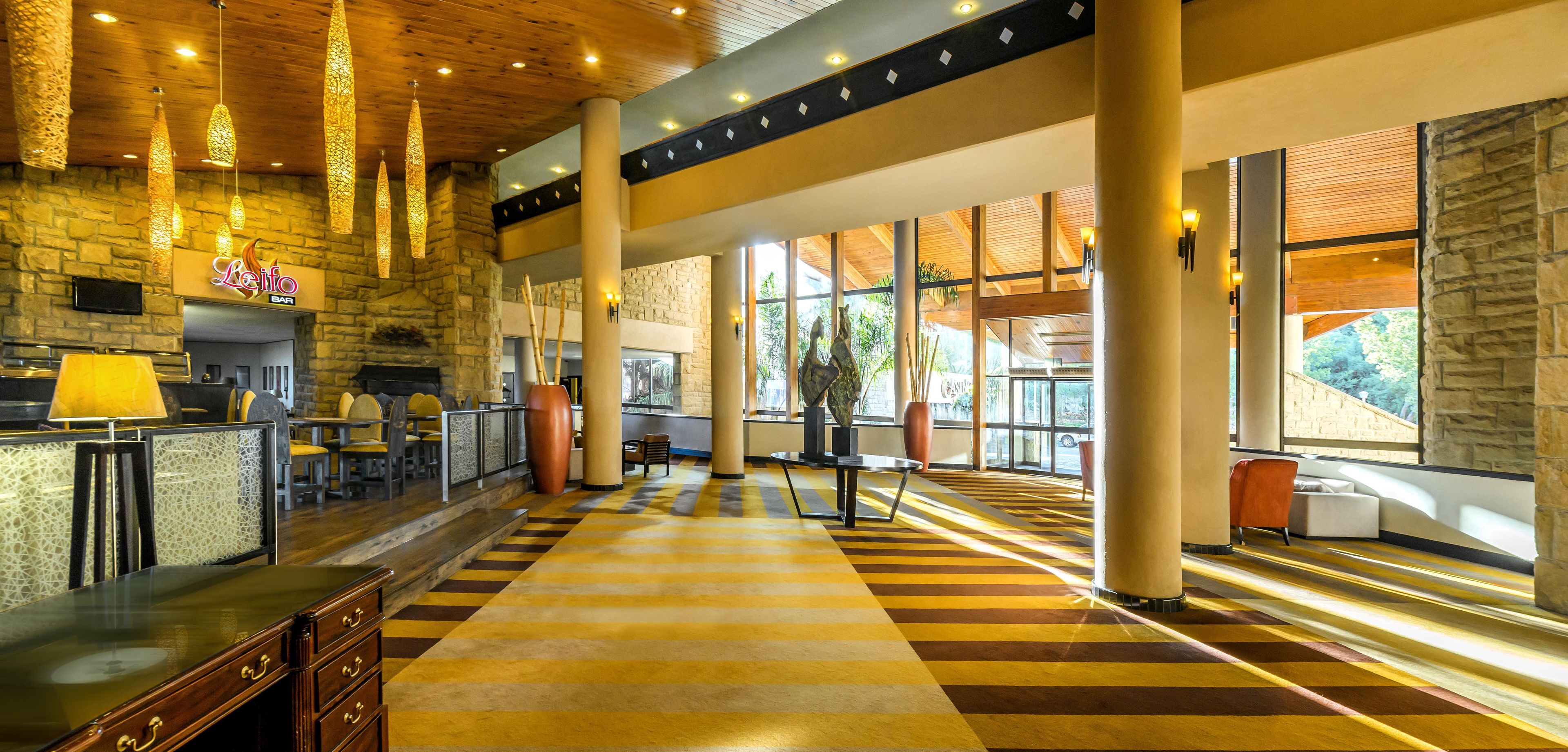 A spacious lobby with a checkered floor, stone walls, and a bar area.