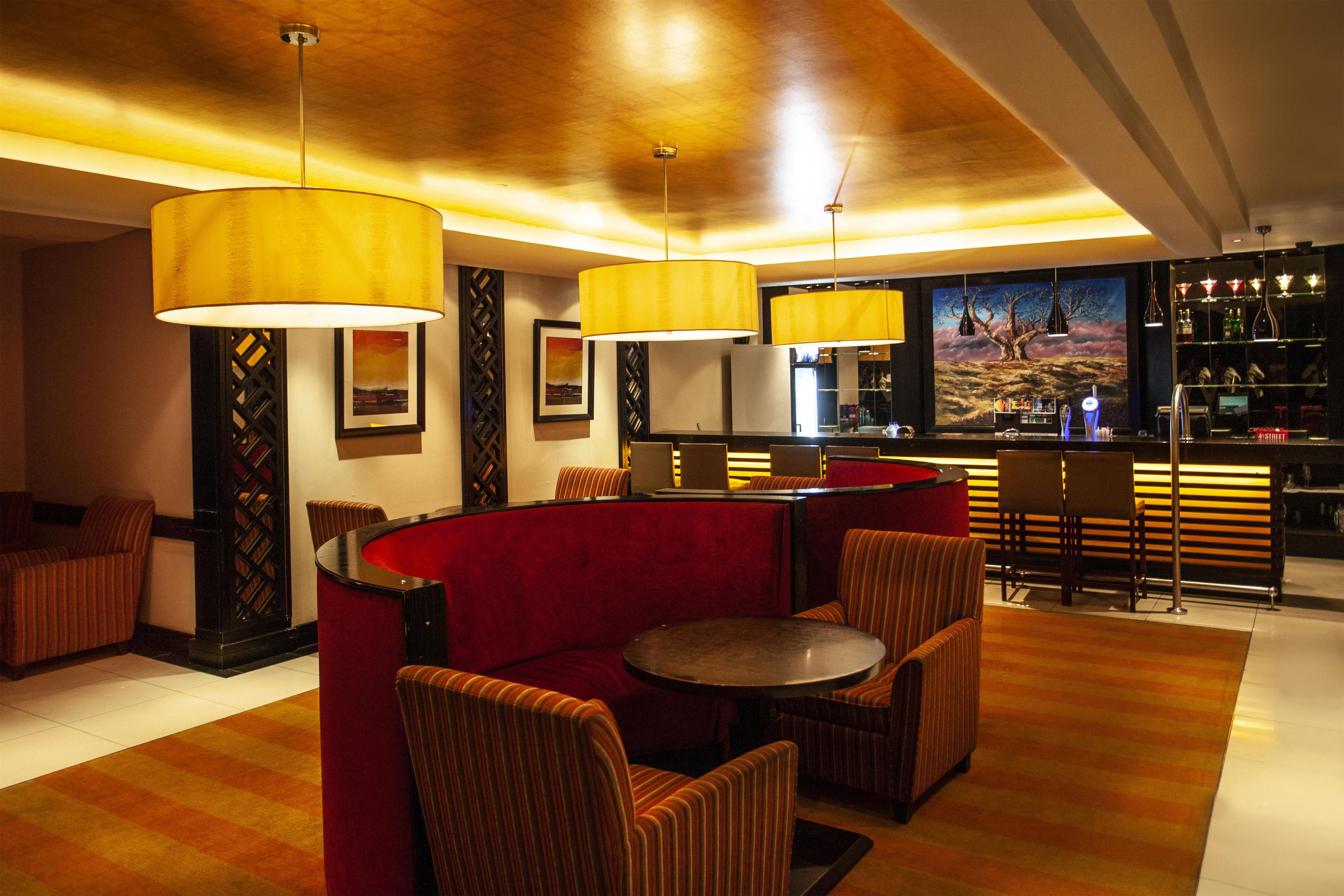 A bar area with seating, a bar counter, and a mural on the wall.