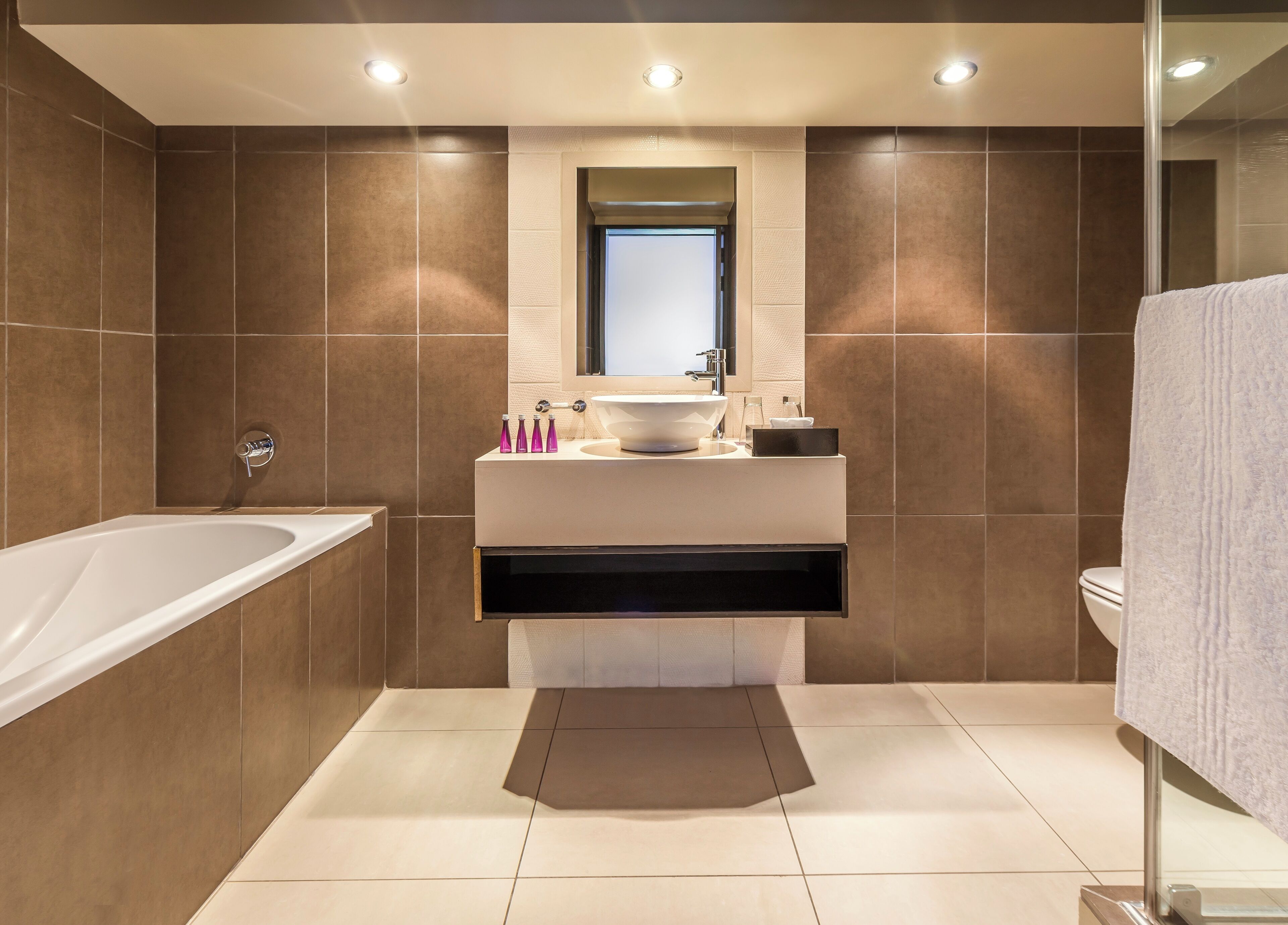 Un baño moderno con una bañera independiente, un tocador con un lavamanos grande y un inodoro.