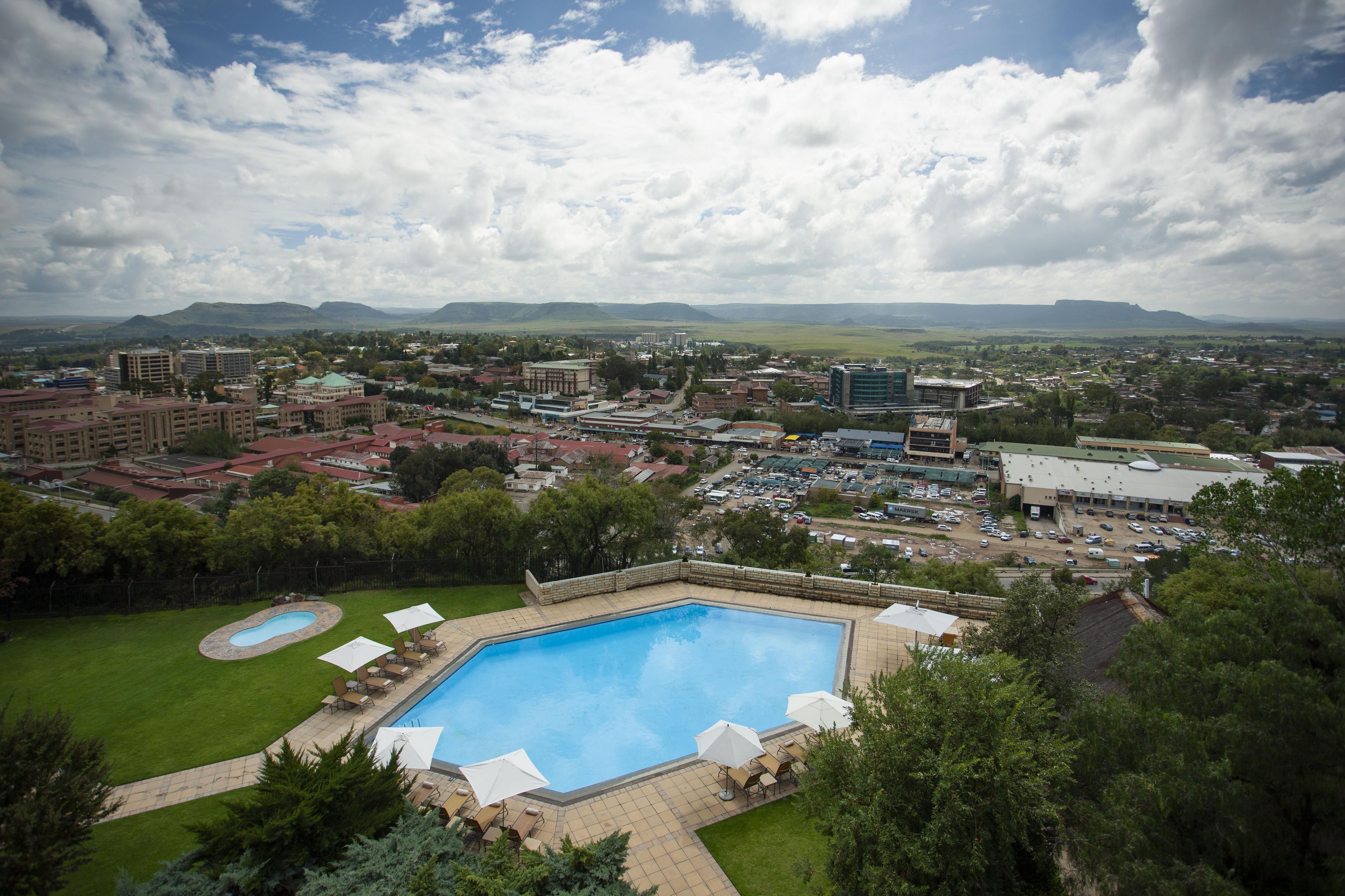A swimming pool with lounge chairs and umbrellas, surrounded by greenery.
