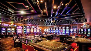 A casino with multiple slot machines, a roulette table, and red bar chairs. - Avani Lesotho Hotel & Casino (Maseru)