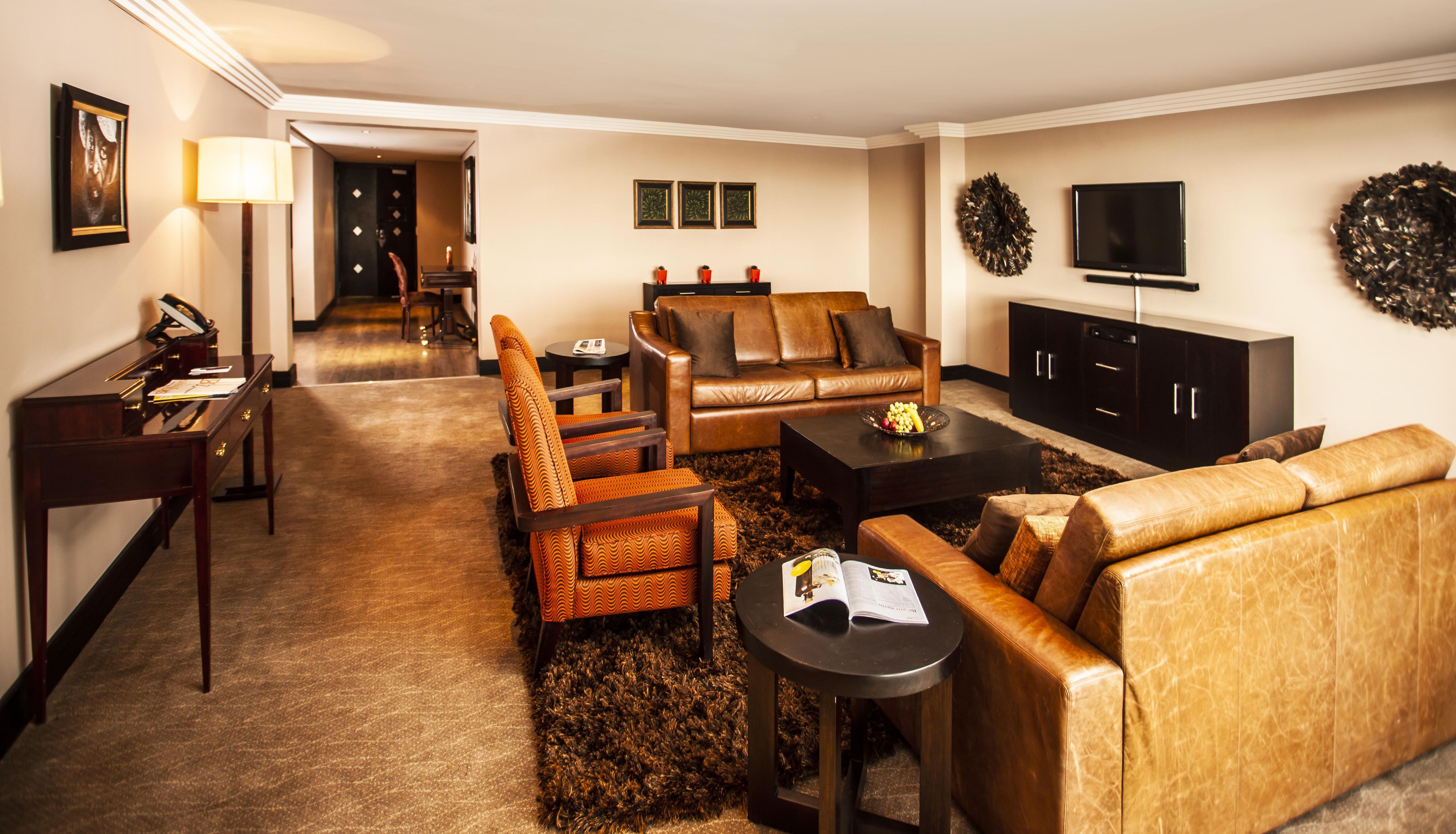 Ein modernes Wohnzimmer mit Ledersofas, einem Couchtisch und einem Flachbildfernseher.