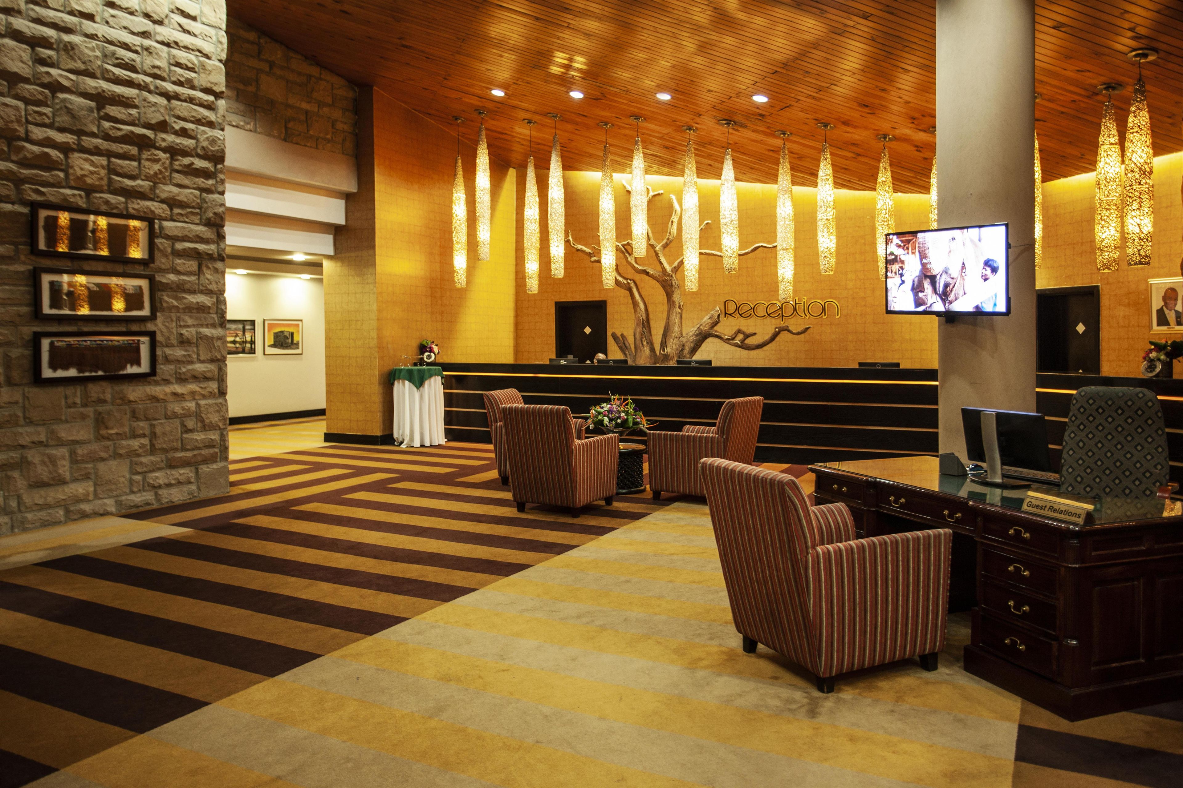 A reception area with a reception desk, chairs, a television, and a patterned carpet.
