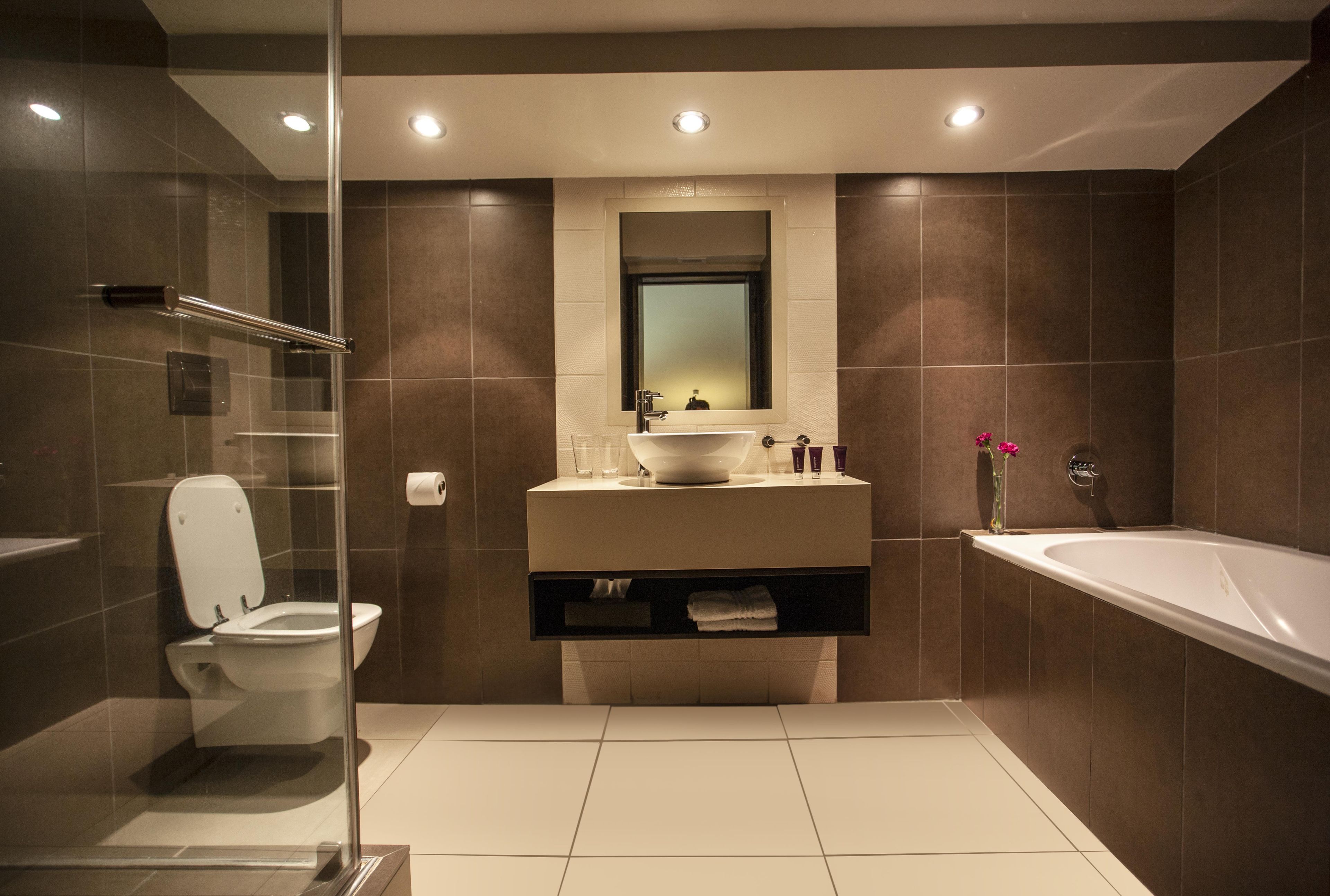 Une salle de bain moderne avec une douche à parois de verre, des toilettes blanches, un meuble-lavabo avec un miroir et une baignoire.
