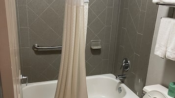 A bathroom with a bathtub, shower, and toilet.
