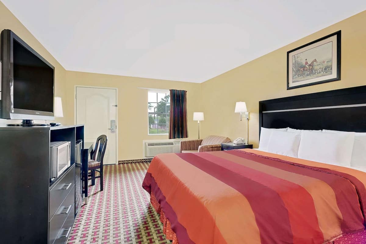 A hotel room with a bed, a TV, a desk, and a chair.