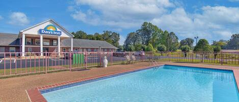 A Days Inn hotel with a swimming pool and a fenced patio area.