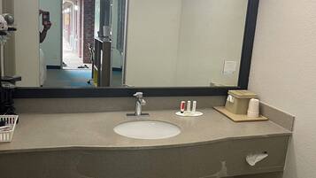 A bathroom with a large mirror, a sink, and a towel rack.