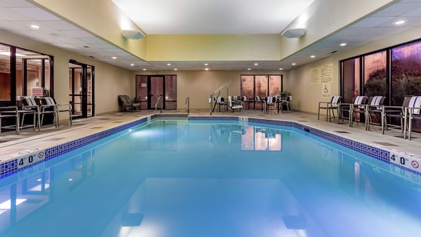 A large indoor pool with a 4'0" depth marking, surrounded by lounge chairs and a staircase leading to an upper level.