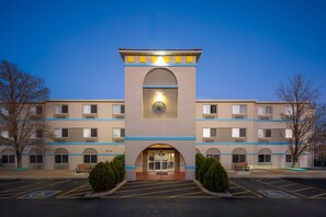 A multi-story hotel with a central arched entrance, a clock above the door, and a parking lot with handicapped parking spaces. - Days Inn & Suites by Wyndham Airport Albuquerque (Albuquerque)