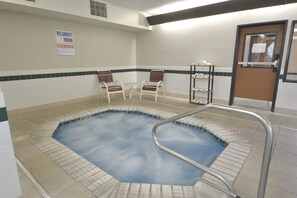 A spa with a hot tub, two chairs, and a shelf with towels. - Days Inn & Suites by Wyndham Airport Albuquerque (Albuquerque)