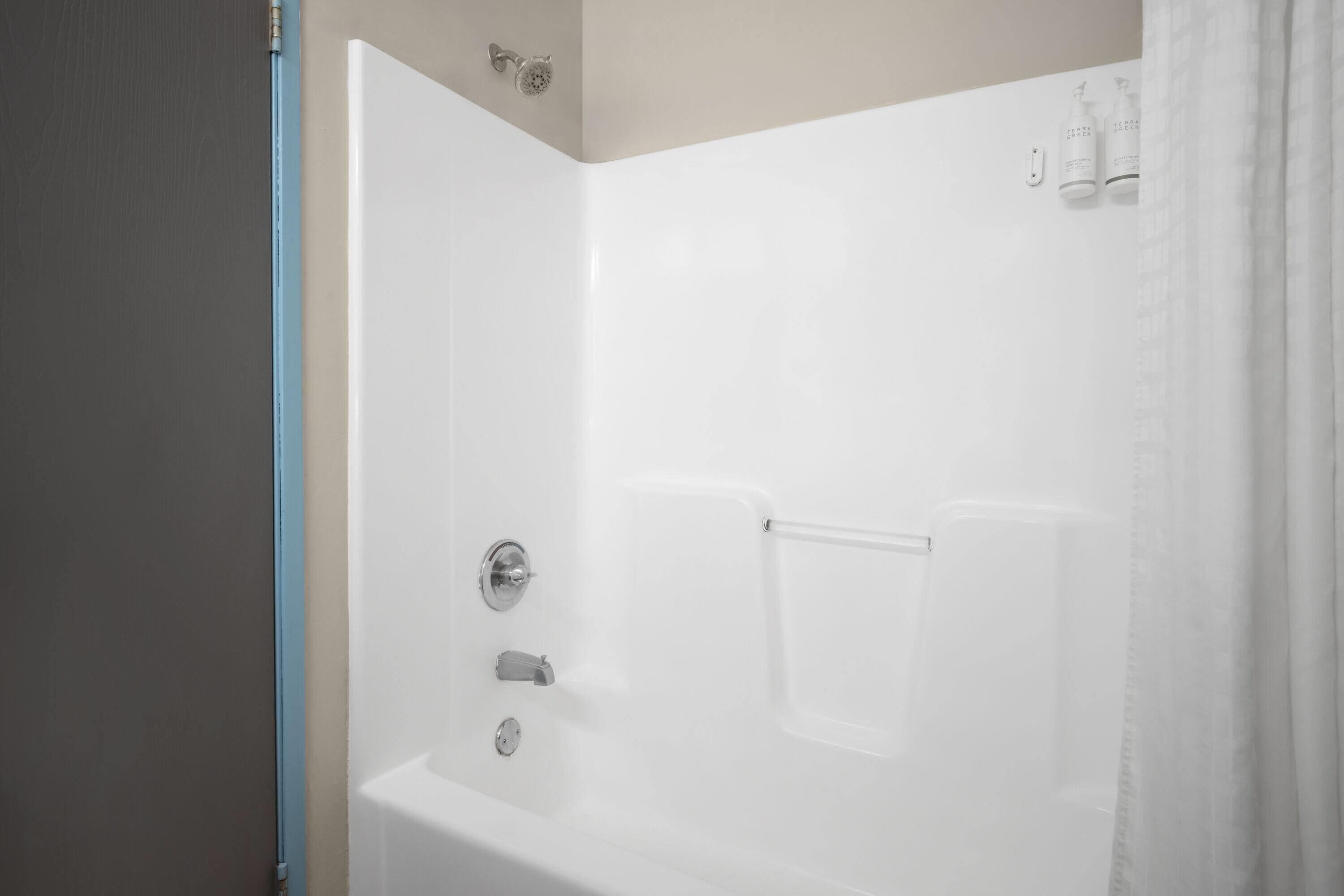 A white bathtub with a showerhead, a faucet, and a control knob.