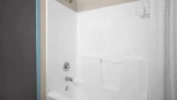 A white bathtub with a showerhead, a faucet, and a control knob.