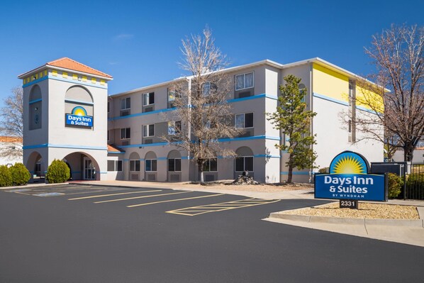 A Days Inn & Suites building with a central tower, multiple balconies, and a parking lot. - Days Inn & Suites by Wyndham Airport Albuquerque (Albuquerque)