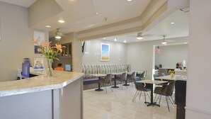 A modern reception area with a counter, seating area, and a view of the kitchen. - Days Inn & Suites by Wyndham Airport Albuquerque (Albuquerque)