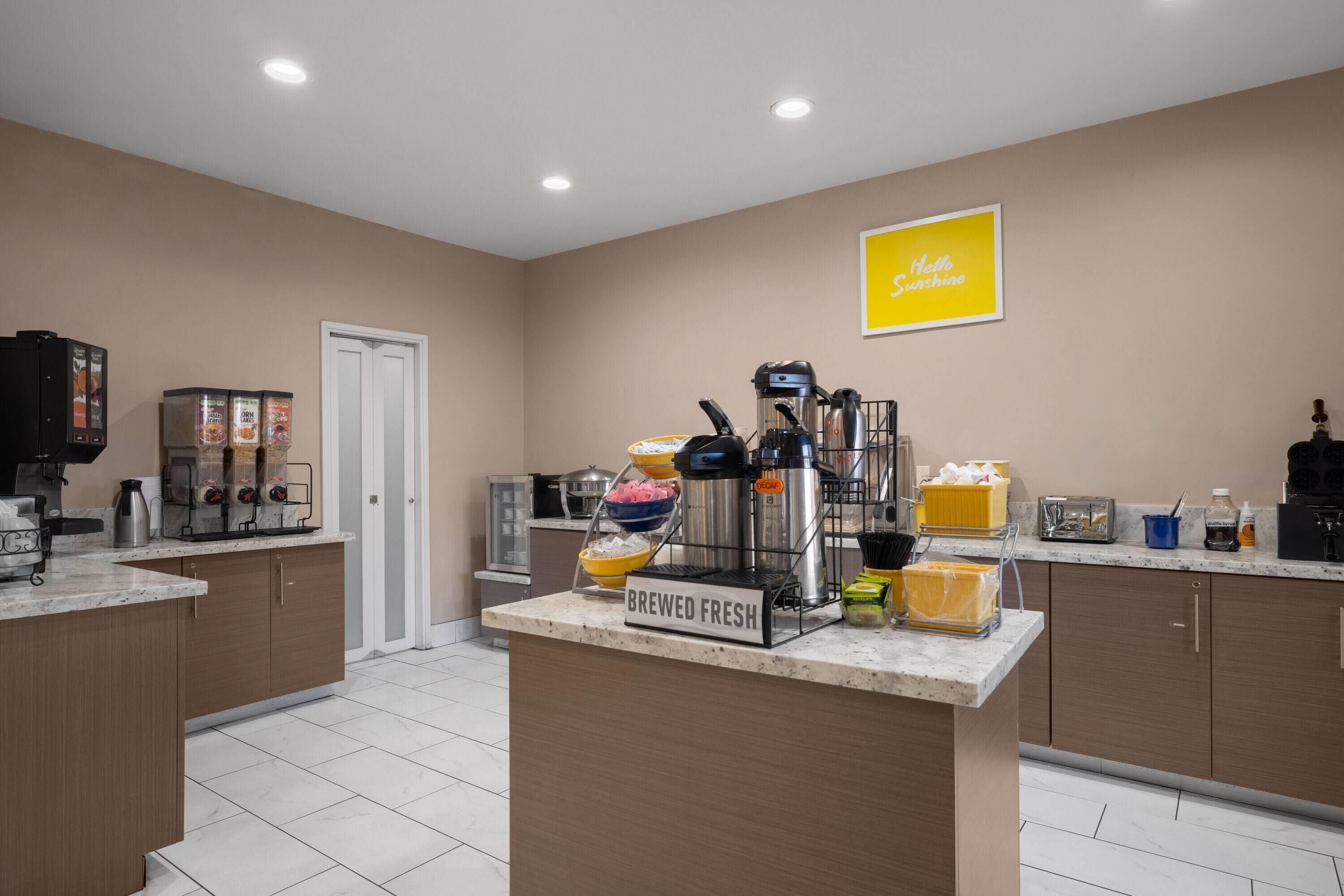 A kitchen with a coffee machine, a kettle, a toaster, and a sign that reads 'BREWED FRESH'.