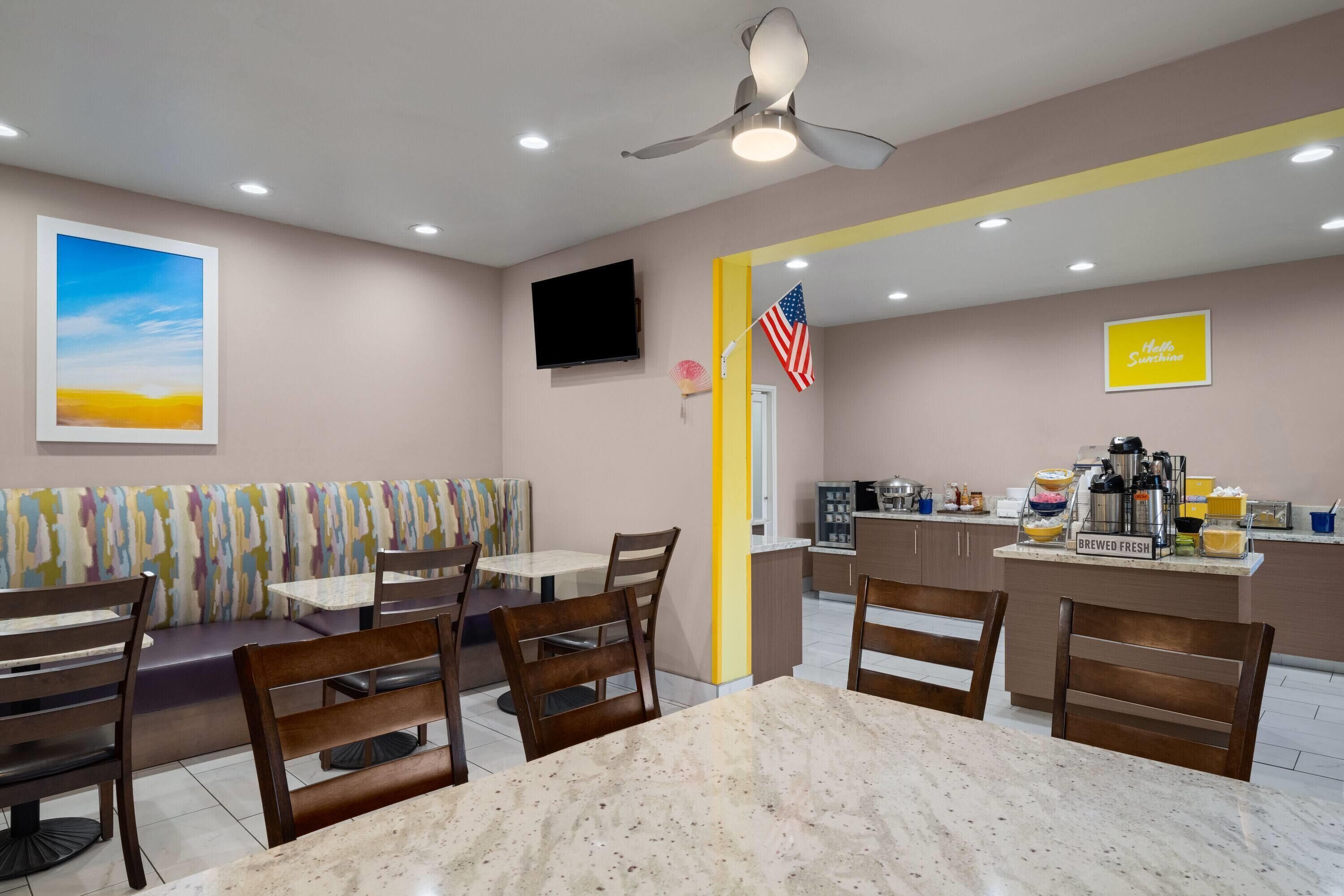 Un restaurante con zona de cabinas, barra con máquina de café y televisor montado en la pared.