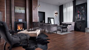 A modern living room with a fireplace, leather furniture, and a bookshelf.
