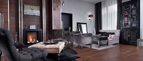 Una sala de estar moderna con chimenea, muebles de cuero y una estantería.