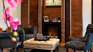 A modern living room with a fireplace, two armchairs, a sofa, and a large wall clock.